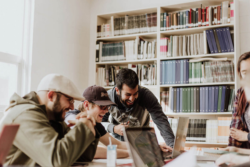 5 Regeln für eine positive Fehlerkultur am digitalen Arbeitsplatz Junges Team das die Hände abklatscht, das sie gemeinsam eine Aufgabe geschafft haben. Beide Männer auf dem Bild sitzen vor einem Schreibtisch